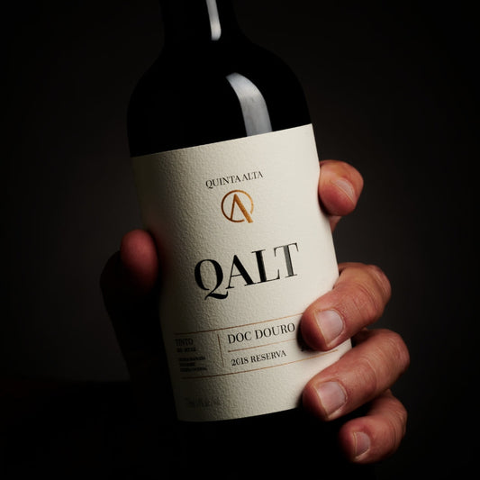 Quinta Alta Qalt Reserva Rotwein in Hand einer Person auf dunklem Hintergrund